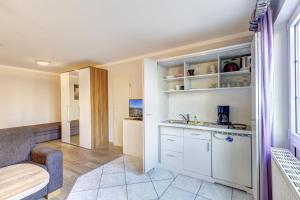 uma cozinha com armários brancos e uma sala de estar em Golz am See 2 em Bansin