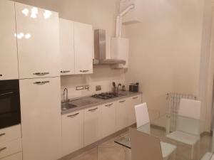 une cuisine avec des placards blancs et une table en verre dans l'établissement Arona Prestige Apartments, à Arona