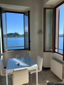 une table et des chaises blanches dans une chambre avec fenêtres dans l'établissement Arona Prestige Apartments, à Arona