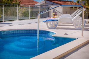 a swimming pool with a table and chairs next to it at Apartments Emil in Lokva Rogoznica