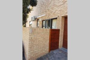 a brick building with a wooden door and a fence at Flamebreeze Corner @ Supertubes Jeffreys Bay in Jeffreys Bay +2 photos