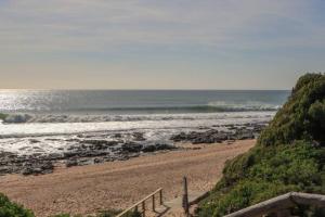 a beach with a staircase leading to the ocean at Flamebreeze Corner @ Supertubes Jeffreys Bay in Jeffreys Bay