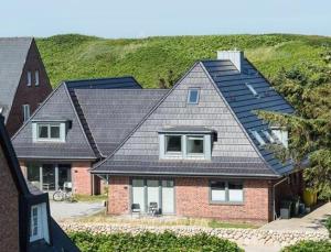 ein Haus mit schwarzem Dach in der Unterkunft Meeresrauschen - Landhaus Tadsen in Westerland