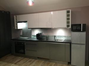 a kitchen with white cabinets and a black counter top at L EDEN et sa love room avec balnéothérapie in Maisons-Alfort