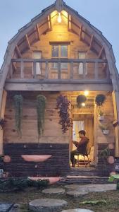 um homem sentado numa cadeira fora de uma cabana de madeira em Villa Lorong Sempit Puncak 2000 Siosar em Pertibi