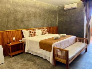 a bedroom with a large bed and two chairs at Hotel Casa do Mar in Icapuí