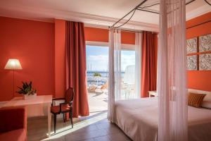 a hotel room with a bed and a desk and a window at Lu' Hotel Carloforte in Carloforte +76 photos