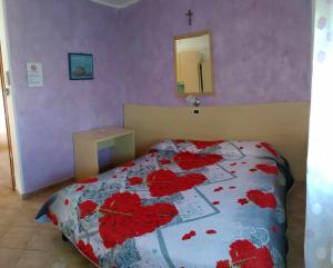 una camera da letto con un letto con fiori rossi di Agriturismo La Fraterna a Tolle
