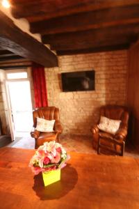 a living room with two chairs and a table with flowers at Auberge Les Tilleuls in Vincelottes