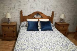 a bedroom with a bed with blue pillows and two tables at Casa rural con piscina privada Manitaga. in Tuineje +24 photos