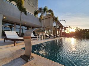 a swimming pool with a fountain in front of a building at Class Hotel Piracicaba in Piracicaba