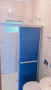 a bathroom with a blue shower door and a toilet at Nacional Park Hotel Lages in Lages