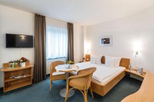 um quarto de hotel com uma cama, uma mesa e cadeiras em euvea Freizeit- und Tagungshotel em Neuerburg