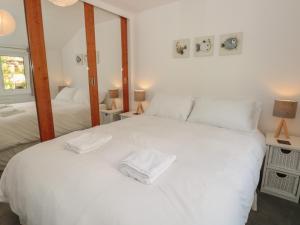 1 dormitorio con 1 cama blanca grande y 2 espejos en George Cottage en Dartmouth