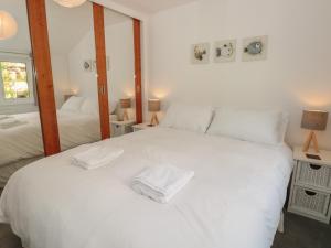 a bedroom with a large white bed with two mirrors at George Cottage in Dartmouth