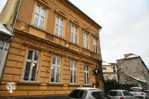 a brown building with cars parked in front of it at Agape Villa Boutique Hotel in Novi Sad