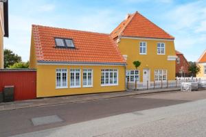 una casa amarilla con techo naranja en una calle en 2 Centralt beliggende og lyst indrettet lejlighed en Skagen