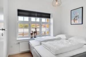 1 dormitorio blanco con 2 camas y ventana en 2 Centralt beliggende og lyst indrettet lejlighed en Skagen
