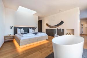 a white bedroom with a bed and a tub at Aura Chalets - Nr 4 in Castelrotto
