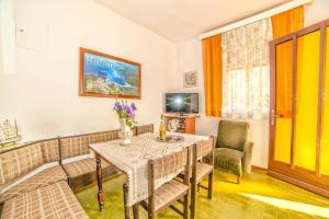uma sala de estar com uma mesa e cadeiras e uma televisão em Apartments Poljak em Rabac
