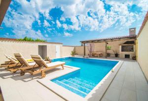 a swimming pool with lounge chairs next to a house at Holiday House Eleonora in Barban