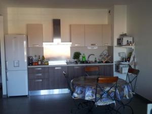 a kitchen with a table and chairs and a refrigerator at Jardins de Quatrina in Propriano