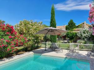 a patio with an umbrella and chairs next to a swimming pool at Villa GOHY in Séguret