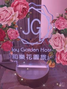 a sign for a vase with flowers on a table at Joy Garden Hotel in Kaohsiung