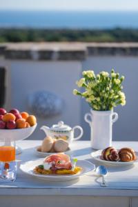 a table with plates of food and a vase of flowers at Borgobianco Resort & Spa Polignano - MGallery Collection in Polignano a Mare