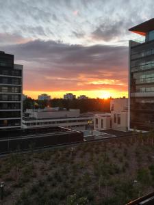 a sunset in a city with buildings and the sun at Tapiola Oak Apartment in Espoo