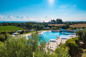 a pool with umbrellas and the ocean in the background at Borgobianco Resort & Spa Polignano - MGallery Collection in Polignano a Mare