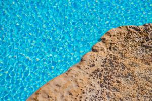 a rock next to a pool of blue water at Borgobianco Resort & Spa Polignano - MGallery Collection in Polignano a Mare