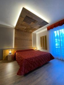 a bedroom with a bed with a red bedspread at Hotel Ciampian in Moena