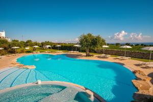 a large swimming pool with chairs and umbrellas at Borgobianco Resort & Spa Polignano - MGallery Collection in Polignano a Mare
