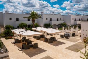 a patio with umbrellas and tables in front of a building at Borgobianco Resort & Spa Polignano - MGallery Collection in Polignano a Mare