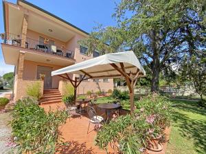 un patio con una sombrilla blanca frente a una casa en La Mimosa en Bolgheri