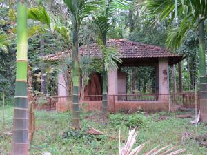 a small house in a garden with palm trees at Sugamya Farm Guesthouse in Sāgar