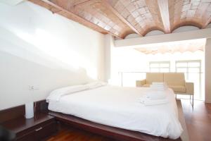 1 dormitorio con cama blanca y techo de madera en LetsGo Paseo de Gracia, en Barcelona