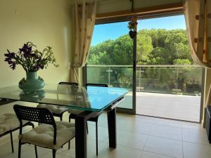 une salle à manger avec une table en verre et une grande fenêtre dans l'établissement Delightful vacations apartment in Algarve, à Olhos de Água