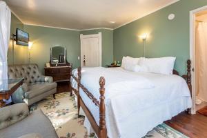 a bedroom with a large bed and a chair at Bath Street Inn in Santa Barbara