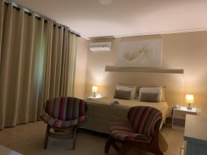 - une chambre avec un lit et deux chaises dans l'établissement Pousada VIP, à Pôrto Real