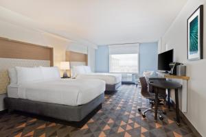 Holiday Inn & Suites Across From Universal Orlando, an IHG Hotel في أورلاندو: غرفة فندقية بسريرين ومكتب