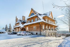 duży drewniany dom z śniegiem na dachu w obiekcie Apartamenty na Leśnej w Bukowinie Tatrzańskiej