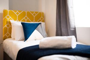 a bed with blue and white pillows and a window at Work-Ready Stay - Central - Parking & Smart TVs in Swansea