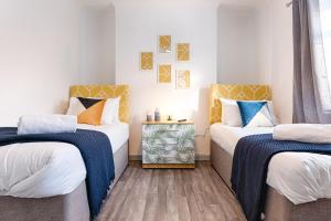 two beds in a room with white walls at Work-Ready Stay - Central - Parking & Smart TVs in Swansea +24 photos