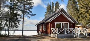 een kleine rode hut met een veranda aan een meer bij Kaijansaaren Lomamökit in Tölvä