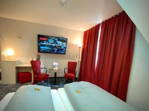 um quarto de hotel com uma cama e uma cortina vermelha em Meister BÄR HOTEL Fichtelgebirge em Marktredwitz