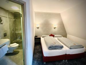 a hotel room with two beds and a toilet at Meister BÄR HOTEL Fichtelgebirge in Marktredwitz