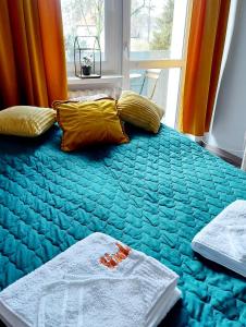 a bedroom with a blue bed with yellow pillows and a window at Apartament Wągrowiec, Gabi - Remigiusz Kiszka in Wągrowiec
