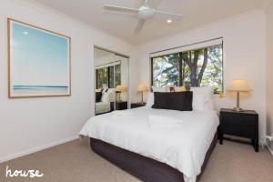 a bedroom with a large white bed and windows at Farm Stay - Tweed Coast Holidays® in Clothiers Creek